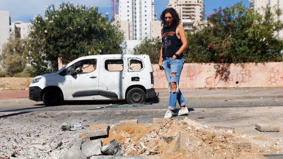 A woman looks at a remnant of a rocket launched from Gaza that is lying on the ground, in Ashkelon, Israel