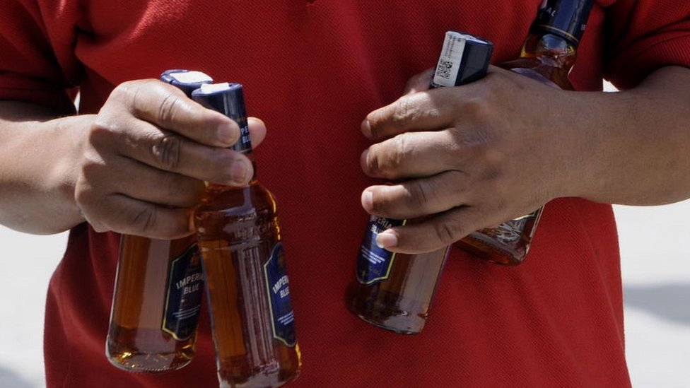 Indian man with alcohol bottles