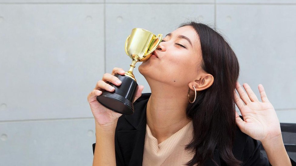 Mujer besando un trofeo