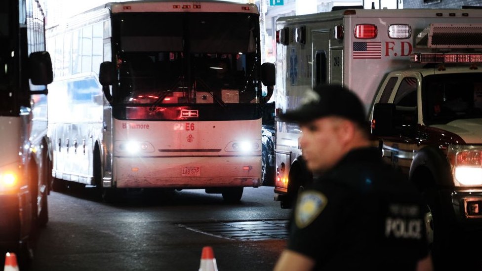 Un policía está parado frente a un autobús de migrantes procedentes de Texas.