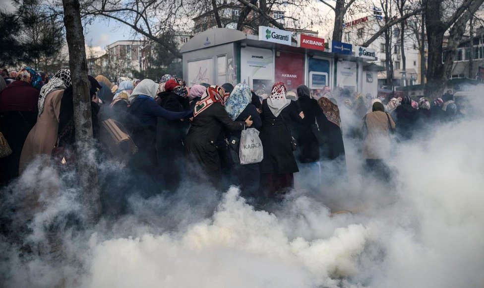 Mujeres corriendo entre gases lacrimógenos