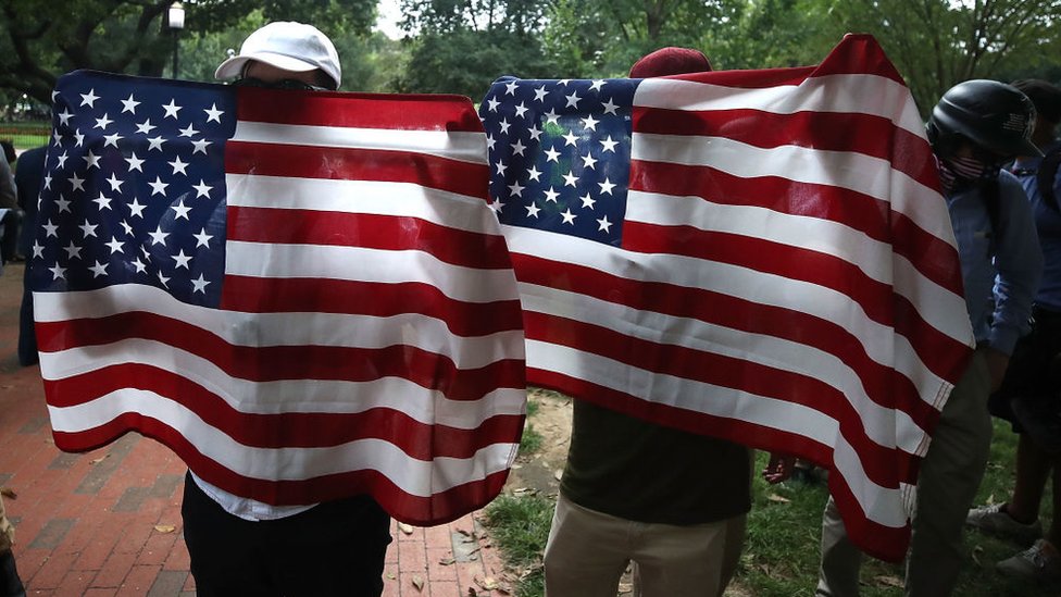 Personas detrás de banderas de Estados Unidos al aire libre