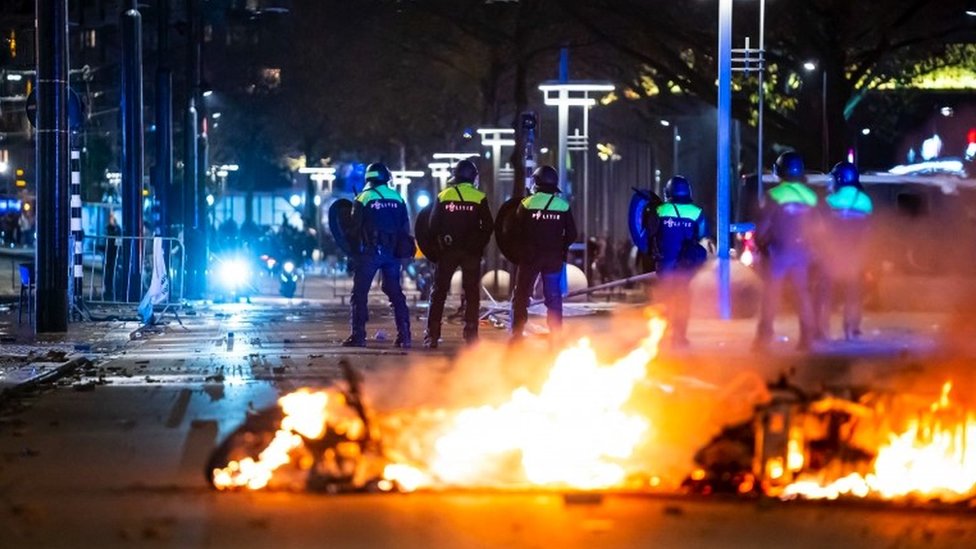 Police stand by burning objects on a street
