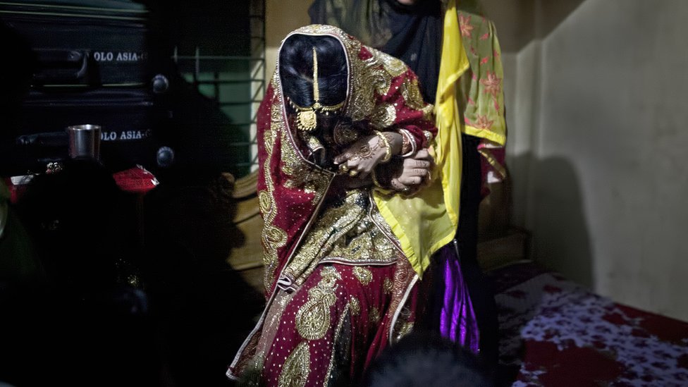 Фотография из архива: родственница пытается затащить 15-летнюю девушку на кровать, чтобы она позировала для фотографий в день ее свадьбы с 32-летним мужчиной, 20 августа 2015 г. в Маникгандже, Бангладеш