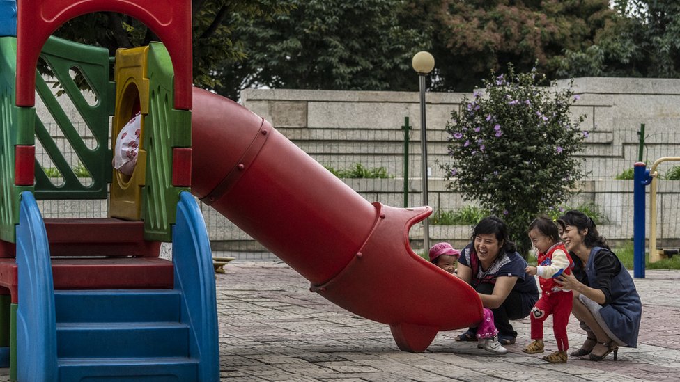 Mothers play on a slide with their children