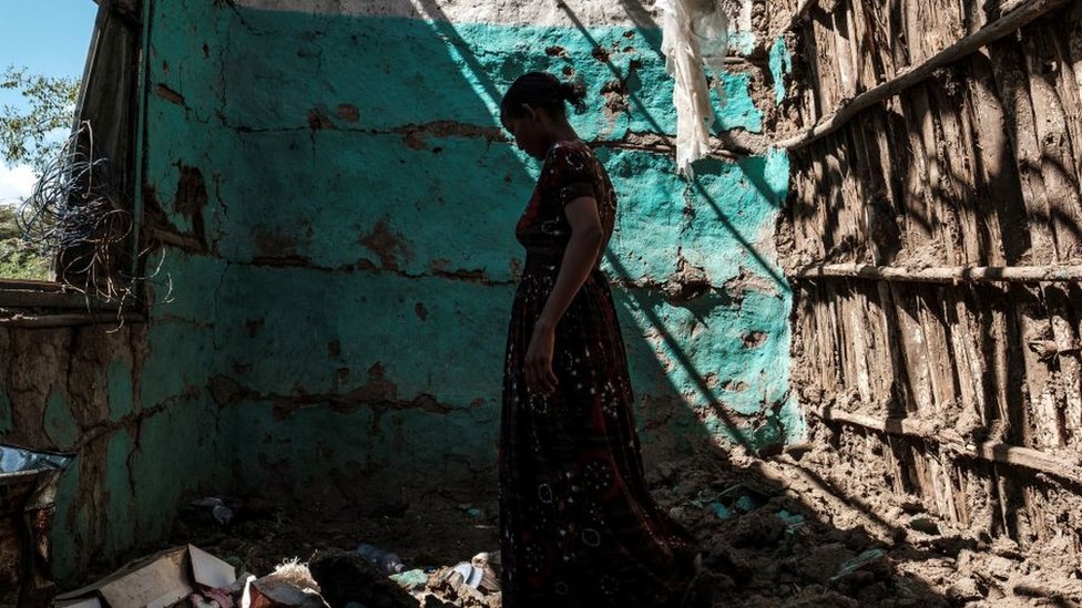A woman walks through her home destroyed by an attack in Tigray.