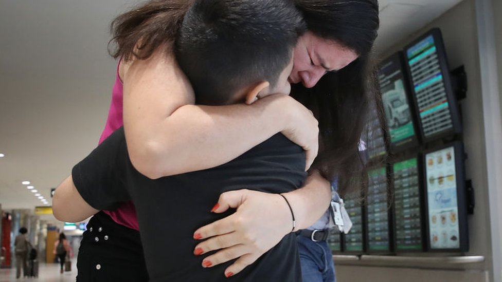 Una madre migrante reunida con su hijo en un aeropuerto de EE.UU.
