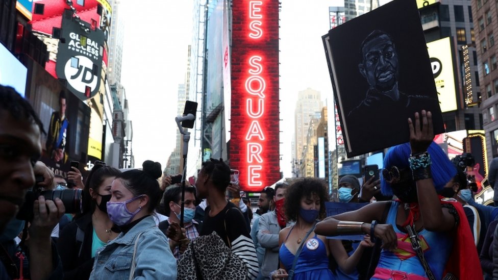 A woman holds a portrait of George Floyd as people celebrate on Times Square