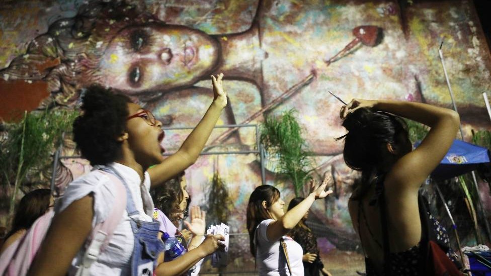 Активисты маршируют за права выбора мимо уличного искусства, вывешенного на стене 28 сентября 2017 года в Рио-де-Жанейро, Бразилия.