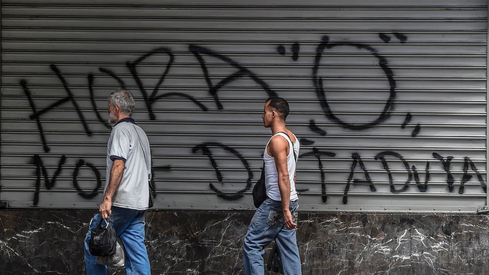 Люди в Венесуэле проходят мимо граффити с надписью на испанском «Нулевой час»