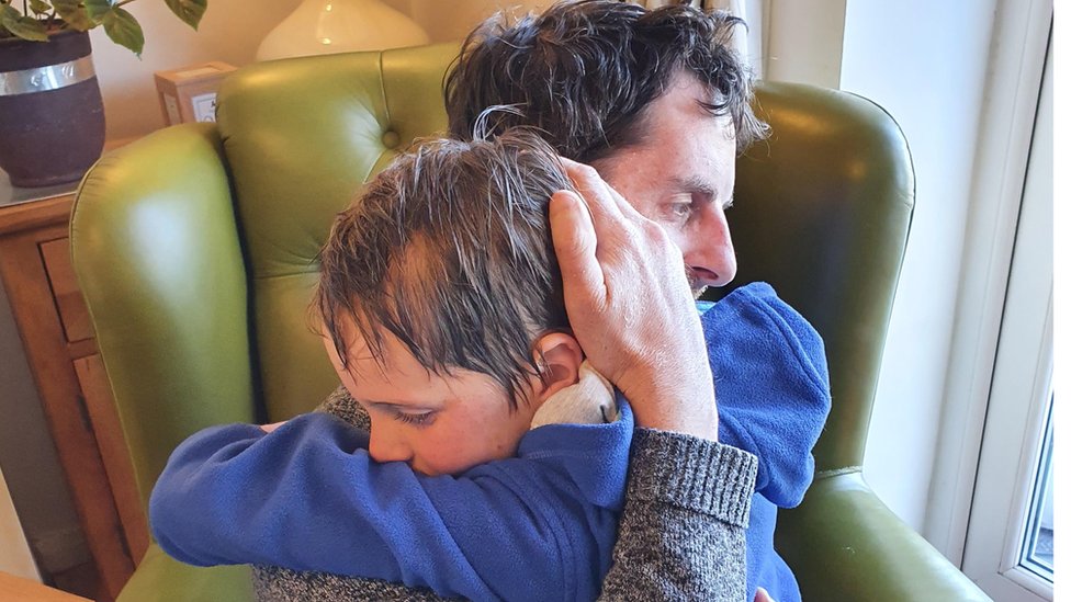 Стивен Лэндон обнимает сына в кресле