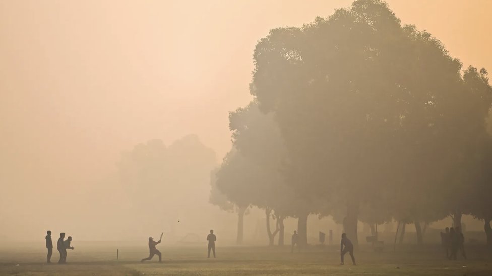 People playing cricket in very heavy smog