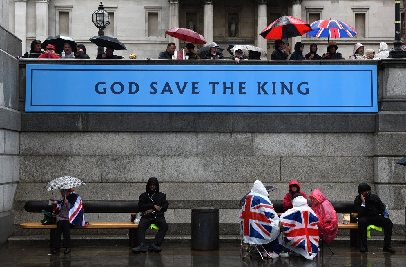 Rain-soaked members of the public take a break during celebrations for the coronation of King Charles III