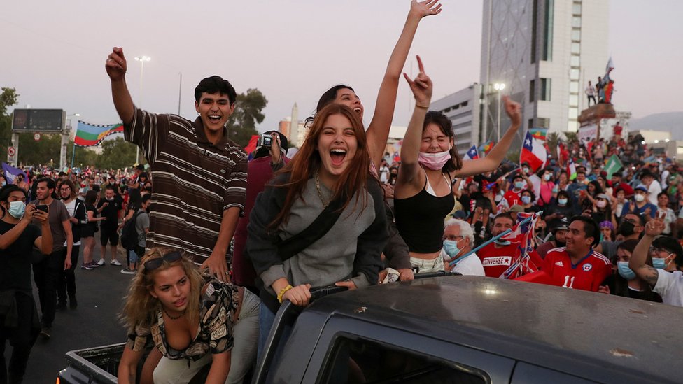 Jóvenes simpatizantes de Boric montados en una furgoneta celebran en una avenida de Santiago. 19 de septiembre de 2021