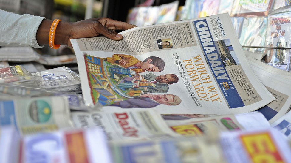Продавец газет раскладывает копии китайского издания своей ежедневной газеты для Африки