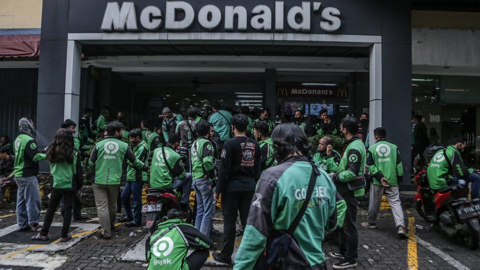 بعض عُمال شركات توصيل الطلبات ينتظرون أمام أحد فروع ماكدونالدز