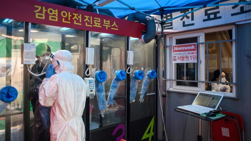 Um homem fala com uma enfermeira durante um novo teste de coronavírus COVID-19 em uma cabine de testes fora do hospital Yangji em Seul em março de 2020