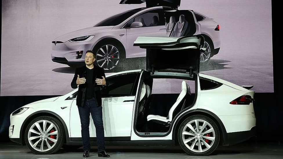 Elon Musk near a Tesla electric vehicle