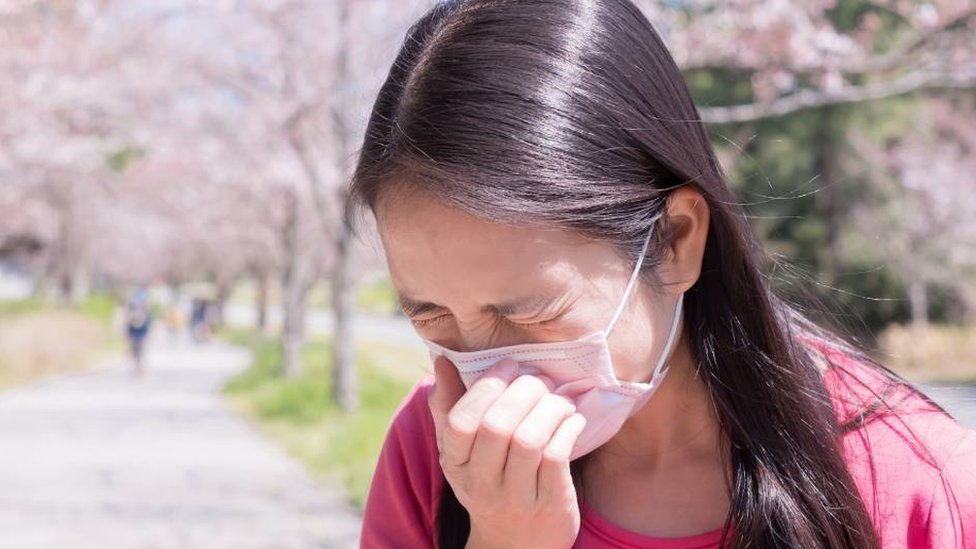 A young Japanese woman sneezing