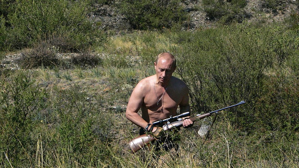 Putin carrying a sniper rifle while hunting topless