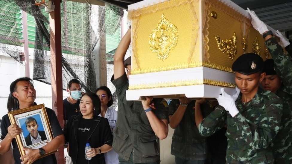 Тайский отец держит портрет своего 13-летнего сына, который был застрелен