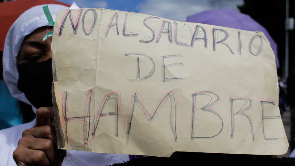 Una enfermera muestra un cartel que dice "No al salario de hambre".