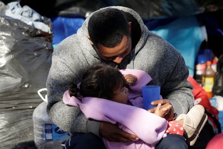 A Mexican man embraces his daughter near the Cordova-Americas international border bridge in Ciudad Juarez while waiting to apply for asylum to the US