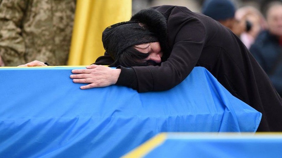 Una mujer en Ucrania llora abrazando el féretro de un ser querido