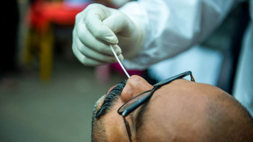 عامل صحي يأخذ مسحة من أنف رجل أثناء اختبار فيروس كورونا، دلهي، الهند