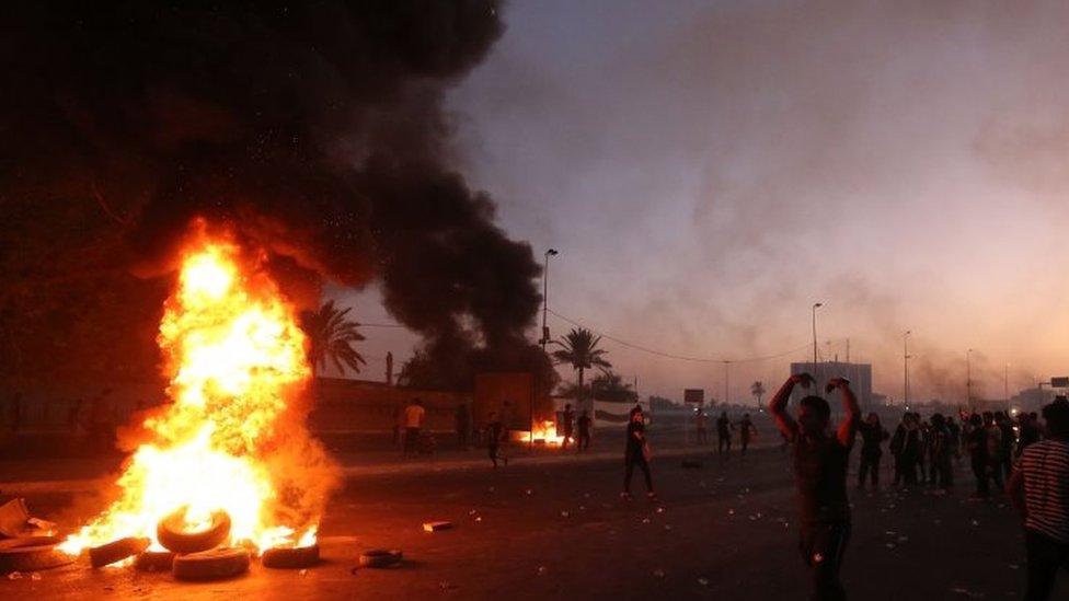 Люди протестуют возле горящих покрышек в Багдаде, Ирак. Фото: 5 октября 2019 г.