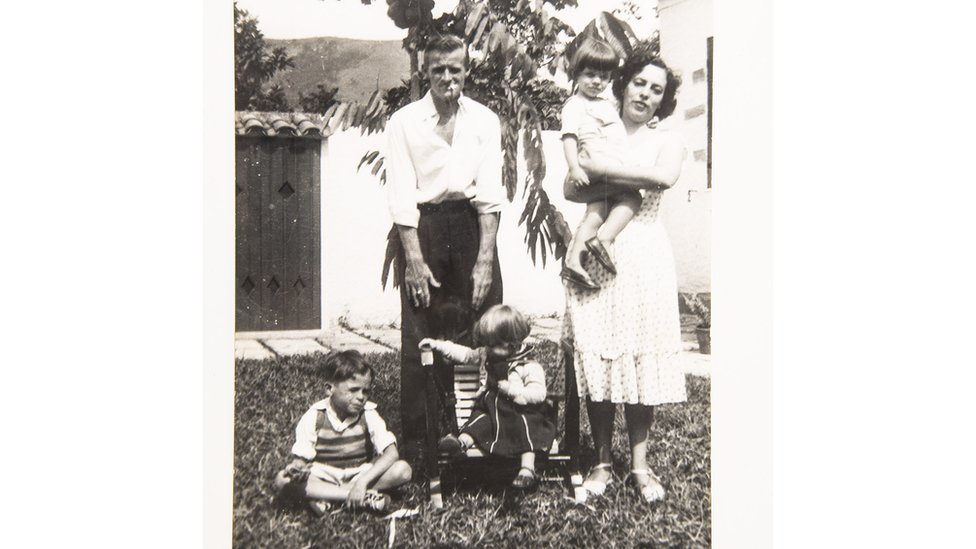 Foto em preto e branco mostra família no jardim