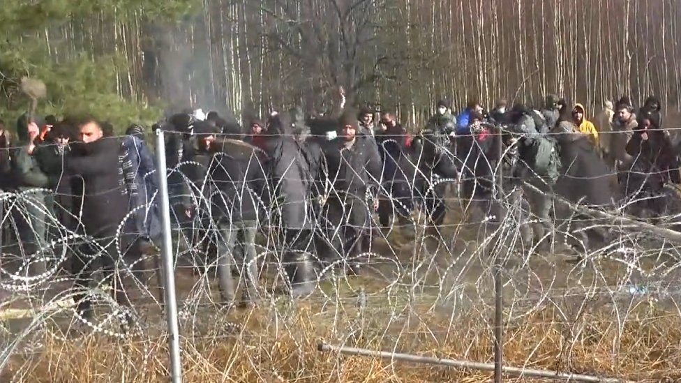 A migrant attempts to break through the barbed wire on Poland's border with Belarus