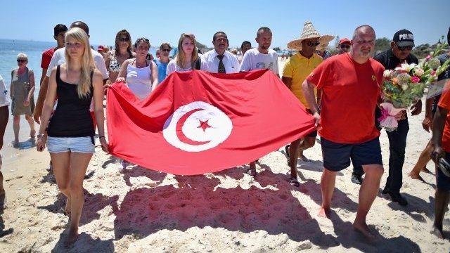 Tourists carry Tunisian flag after terror attack