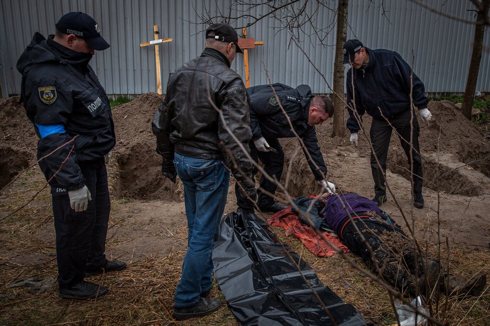 Police in Bucha examine a body unearthed in a field. At least 500 dead have been found since the Russians left.
