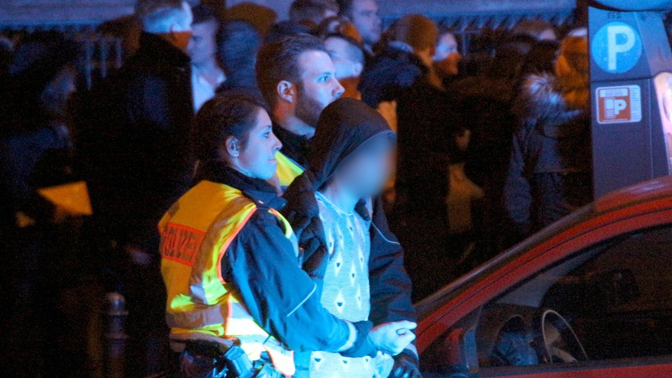 Женщина-полицейский держит молодого человека 31 декабря на вокзале Кельна