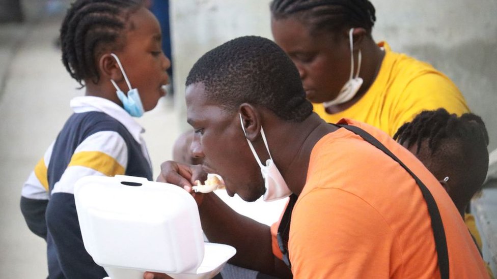 Haitianos repatriando comiendo en el aeropuerto de Puerto Príncipe.
