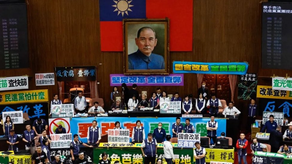Taiwanese lawmakers holding placards chant slogans