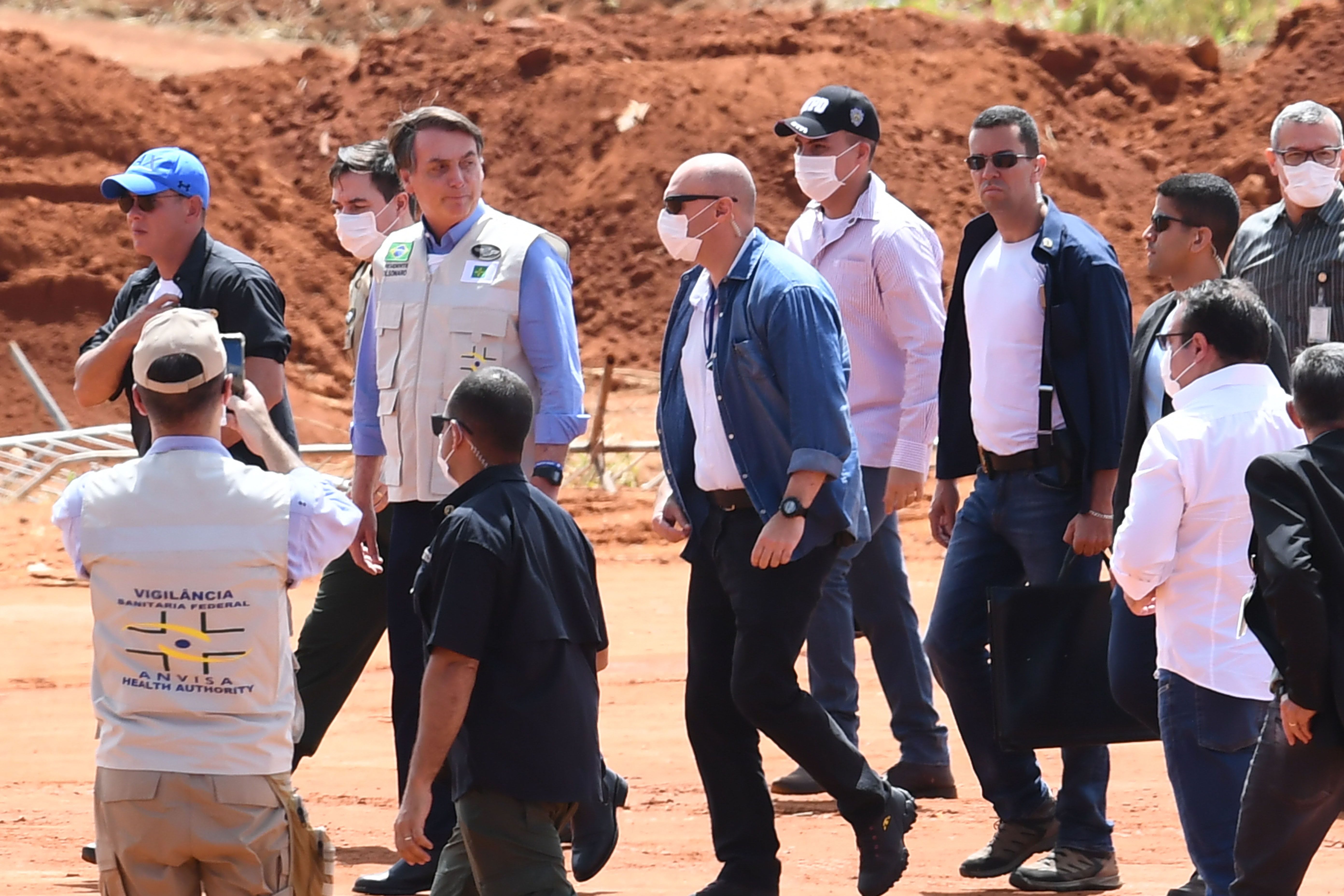 Президент Жаир Болсонару (3-L) посещает строительную площадку полевого госпиталя для людей, инфицированных новым коронавирусом, в Агуас-Линдас, штат Гояс, Бразилия, 11 апреля 2020 года.