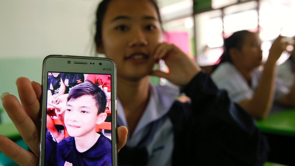 Una estudiante muestra en su celular una foto de Duangpetch Promthep, uno de los niños atrapados