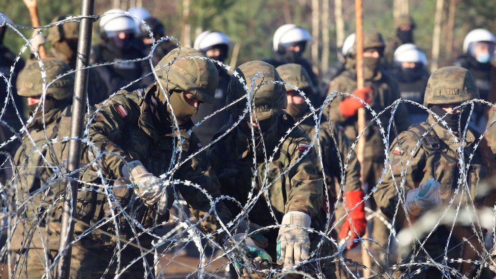 Agentes de policía polacos revisan la cerca de alambre de púas.