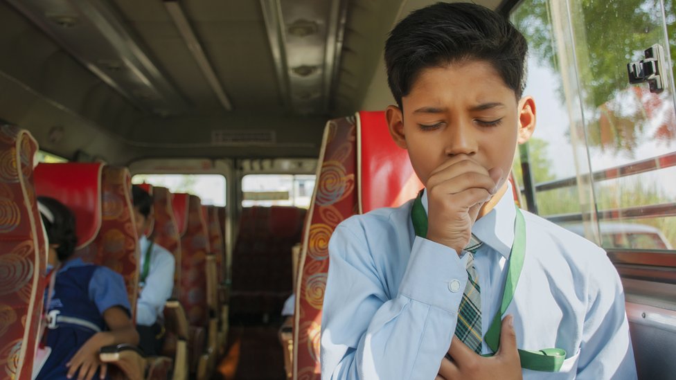 Niño tosiendo en un bus.