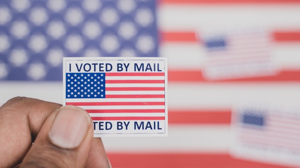 Man holding a 'I voted by mail' sticker