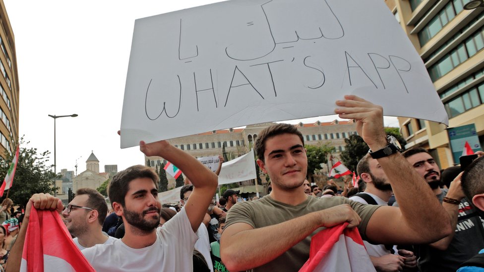 أحد المتظاهرين يحمل لافتة كُتب عليها "لبيك يا واتساب"