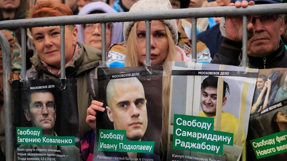 Демонстранты в Москве держат плакаты с лицами заключенных в тюрьму протестующих, которых они требуют освободить в воскресенье, 29 сентября
