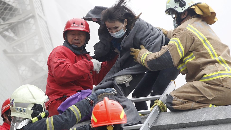 Спасатели помогают выжившему сбежать из обрушившегося здания в Тайнане, Тайвань, 6 февраля 2016 г.