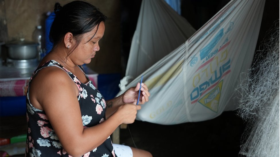 菲律賓巴拉望島上，一名婦女正在修理漁網