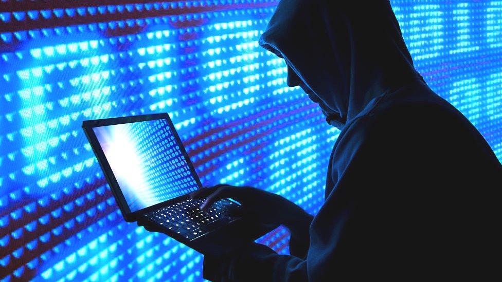Un hombre con una computadora usando una capucha.