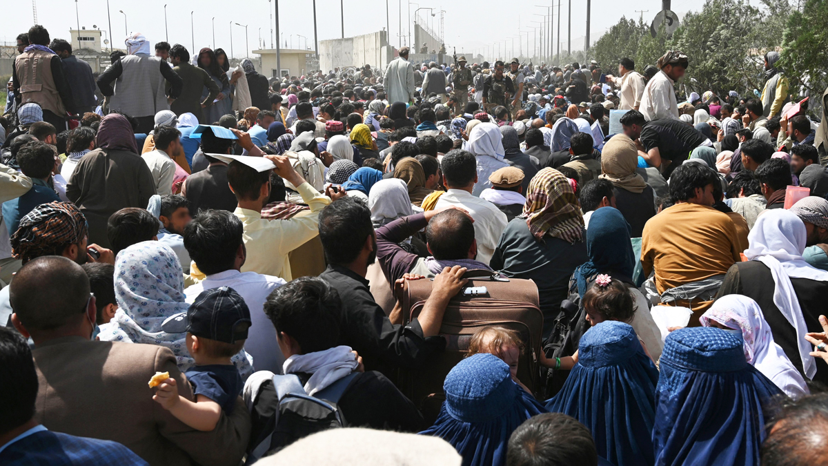Afghans gather on a roadside near the military part of the airport in Kabul, August 20, 2021