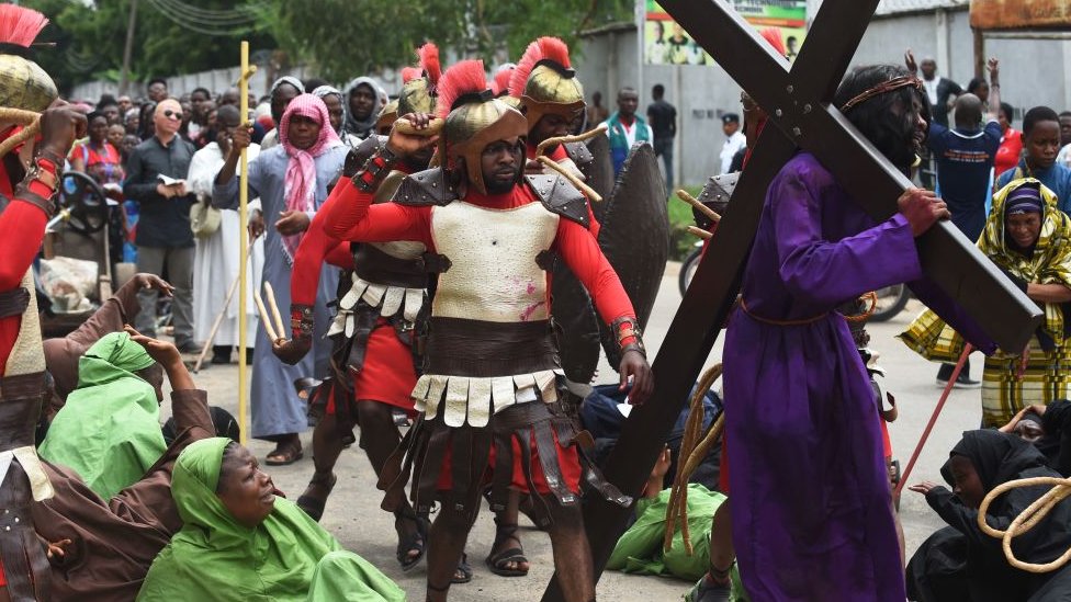 Мужчина, исполняющий роль Иисуса Христа, подвергается избиению, поскольку несет крест во время процессии в честь Страстной пятницы в Лагосе, 14 апреля 2017 года.