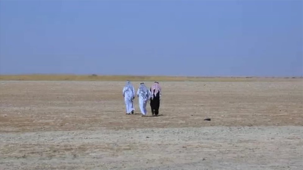 ثلاثة أشخاص يسيرون فوق بحيرة جافة